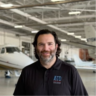 Lute Atieh standing in an aircraft hangar with an ATD Flight Systems aircraft